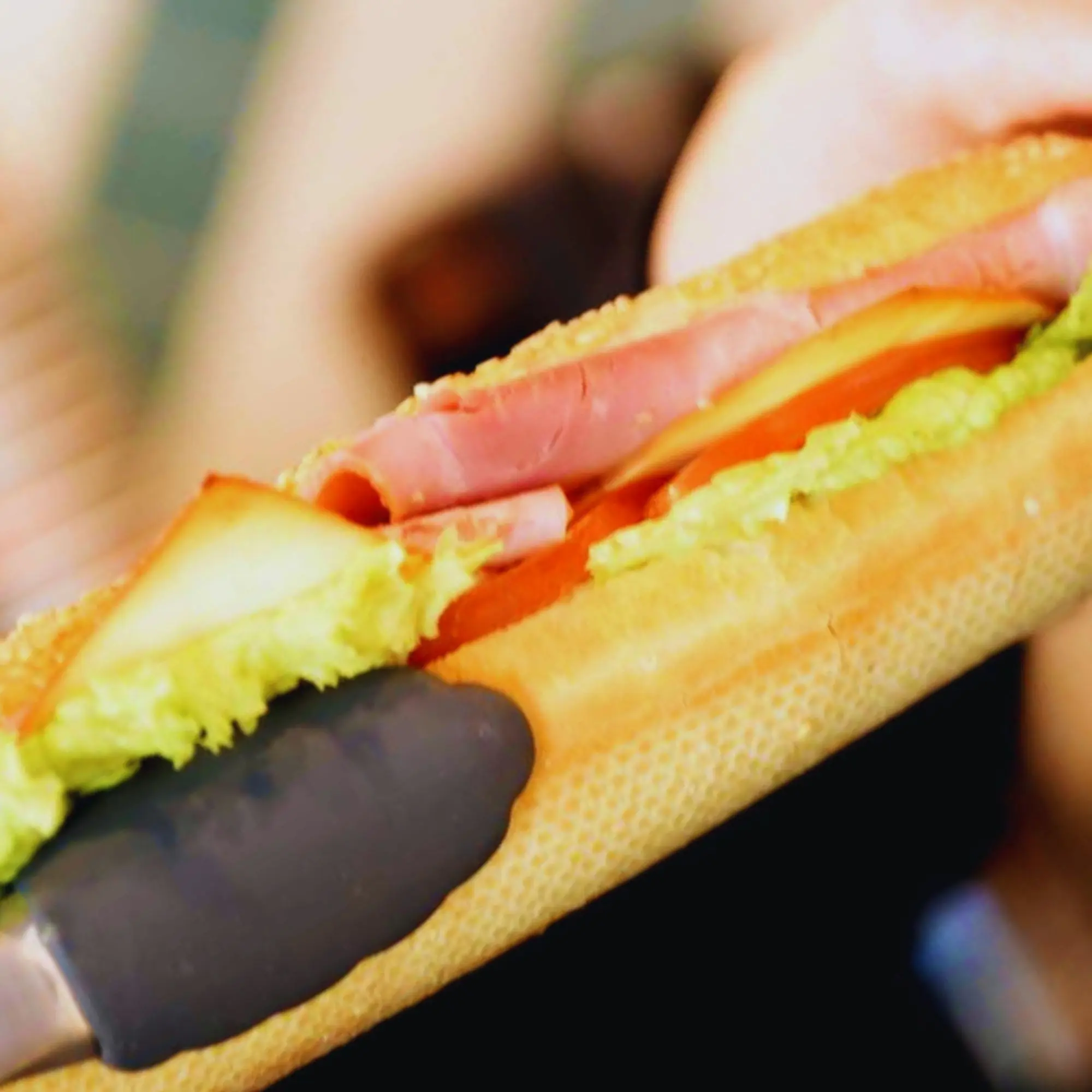 Close-up of a sandwich with egg salad, sliced meat, and lettuce between toasted bread slices